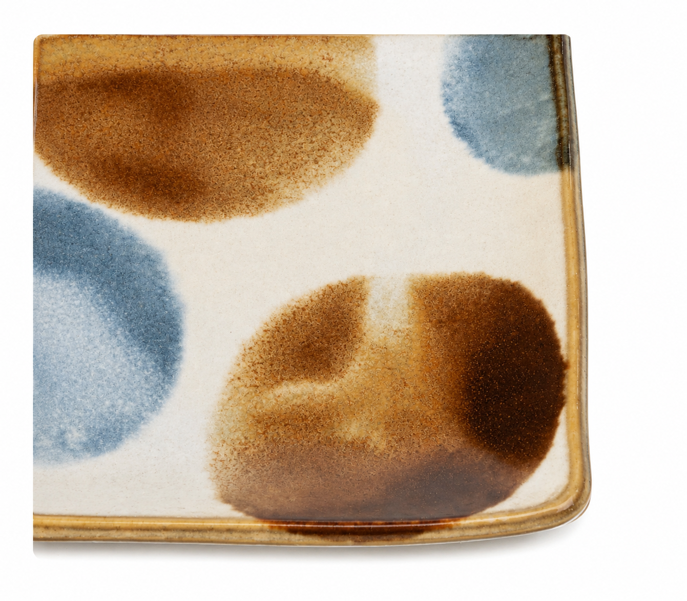 Close-up of ceramic sushi plate surface showing hand-applied blue and brown dot brush glaze pattern with gold rim detail.