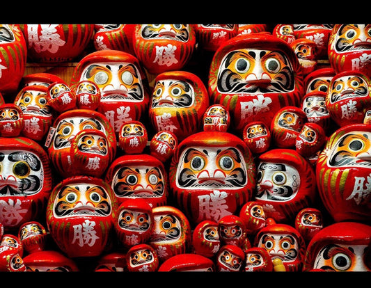 Multiple red Daruma dolls in Japan representing good luck, determination and goal achievement