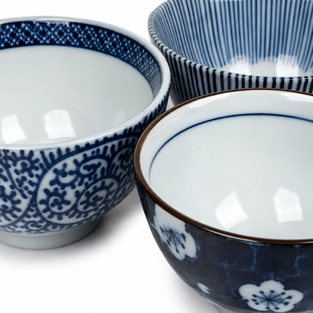 Five Japanese Aizome rice bowls showing exterior patterns including arabesque, dark navy sakura, scattered plum blossom, and stripe designs