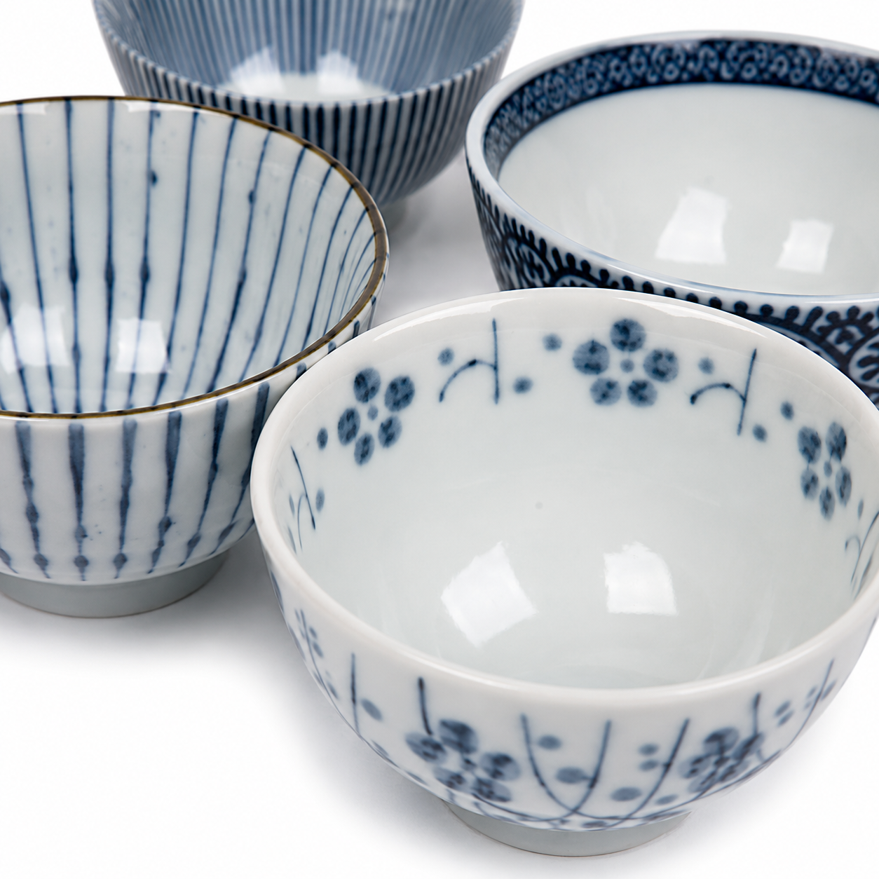 Five Japanese Aizome rice bowls showing exterior patterns including arabesque, dark navy sakura, scattered plum blossom, and stripe designs