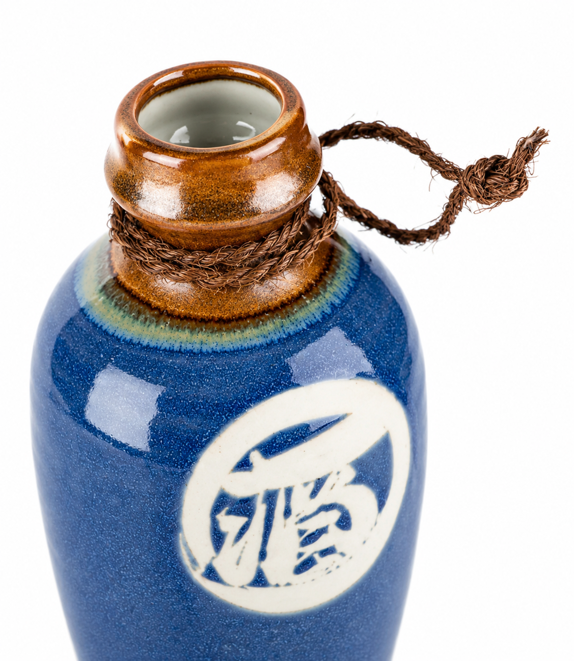 Close-up of Kamakura sake jug neck showing amber glaze, rope detail and kanji 酒 on indigo blue ceramic tokkuri, made in Japan
