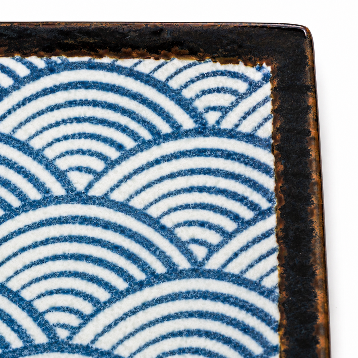 Close-up of Seikaiha wave pattern on Japanese ceramic sushi plate showing detailed indigo blue and white glaze with dark edging, made in Japan