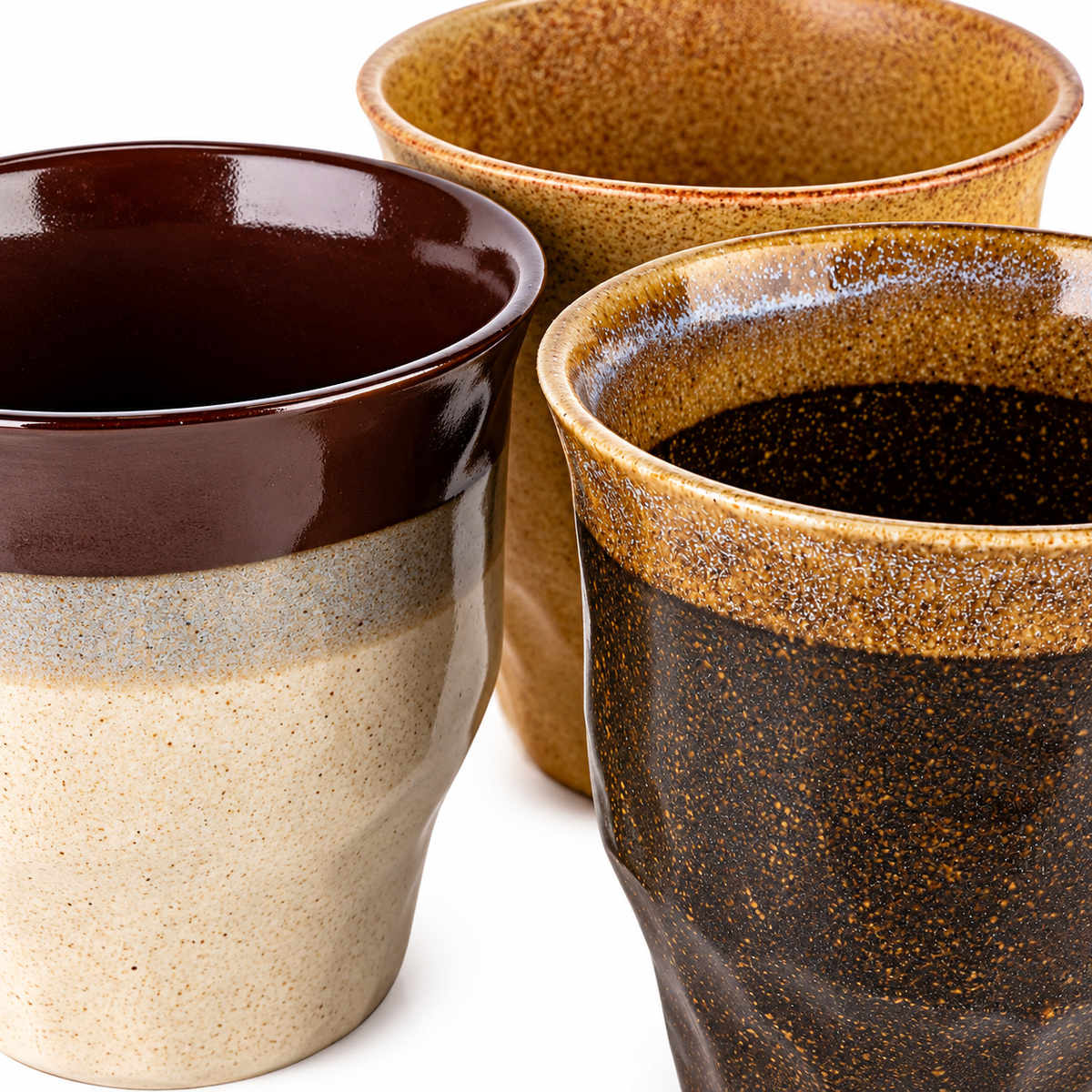 Close-up of the cream cup with a dark brown rim beside the speckled brown cup and ochre cup.