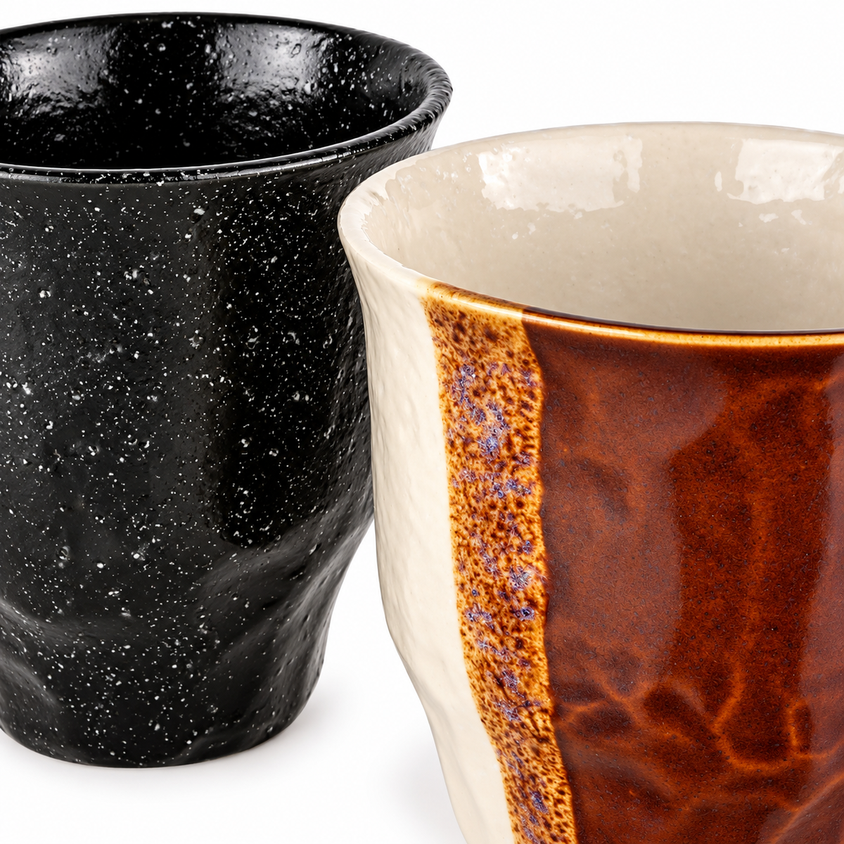 Close-up of the speckled black cup beside the cream and reddish-brown cup.